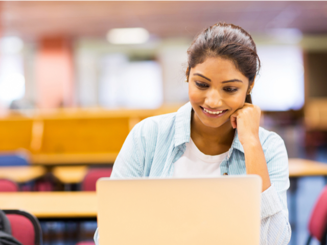 Student smiling looking at a laptop screen